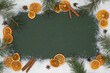 Christmas advent celebration holidays background banner greeting card - Border frame made of ornament, dried orange slices, cinnamon sticks, star anise, pine branches and snow on green table, top view