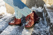 Winter is coming. Winter Female boots on rough slipper ice surface. A woman in vinous leather shoes descends the slippery ice ladder.