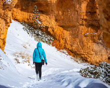 Girl In Blue Jacket Hiking Through Snowdrifts Among Massive Rocks Of Bryce Canyon National Park In Winter; Magical Winter Landscape In Usa, Utah