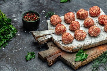 Wall Mural - raw meatballs on wooden board, minced pork meat with spices on a dark background. Food recipe background. Close up