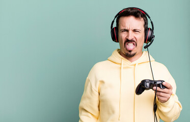 adult man feeling disgusted and irritated and tongue out with headset and a control. gamer concept