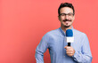 adult man smiling happily with a hand on hip and confident with a microphone. presenter or journalist concept