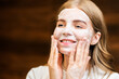 A young caucasian smiling woman is making a face mask