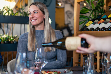 Wall Mural - waiter brings a bottle of quality white wine for a couple, and serve it to the lady in her glass at the restaurant