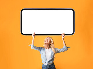 Canvas Print - Young Happy Blonde Woman Holding Big Blank Smartphone Above Head