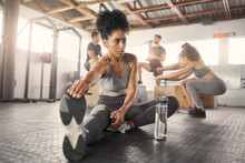 Stretching, Fitness And Training With Black Woman In Gym With Water Bottle For Exercise, Sports And Workout. Health, Wellness And Energy With Girl And Legs Warm Up For Performance, Muscle And Strong