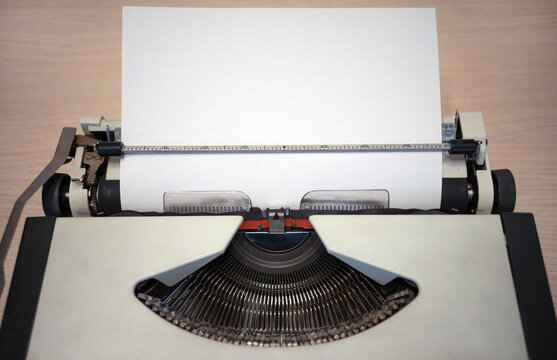 A white sheet of paper sticks out of the typewriter. An old typewriter with a blank sheet of paper.The original white background for the ad. The typewriter is gray with a red ink ribbon.
