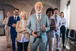 © Mediteraneo - Group of business people with senior businessman leader on foreground
