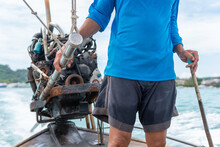 Unrecognizable Man Driving The Rudder And Engine Of An Old Rusty Asian Thai Long Tail Boat.