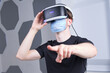 © Евгений Шемякин - Portrait of serious young man, guy using, wearing a modern device virtual reality headset mask 3D, AR, VR glasses, playing the game in medical mask on face. Technology metaverse, coronavirus, covid-19