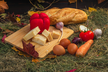 Wall Mural - still life with vegetables and cheese on a cutting board in the hay