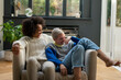 © Cultura Creative - Smiling lesbian couple relaxing on armchair at home