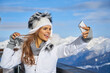 © ZoomTeam - technology and leisure concept - happy woman in winter fur hat taking selfie by smartphone outdoors