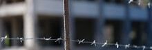 Barbed Wire Fence In Front Of Prison Building Closeup