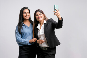 Wall Mural - Two indian businesswoman or manager taking selfie on white background.