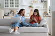 © DimaBerlin - Teen girl child daughter and young mother using gadgets together, sitting on sofa at home. Curious parent mom peeping who kid chatting in social networks. Family and digital technologies concept