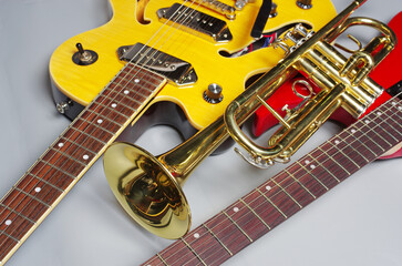 Wall Mural - Yellow, red electric guitars and a golden trumpet on a light background.
