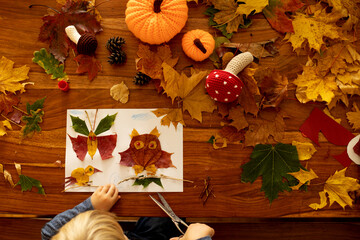 Child, applying leaves using glue, scissors, and paint, while doing arts and crafts at home