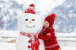 © famveldman - Child building snowman. Kids build snow man.