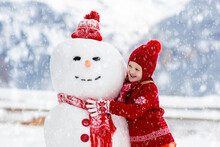 Child Building Snowman. Kids Build Snow Man.
