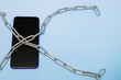 © Елена Белоусова - mobile phone in iron chains on a blue background with copy space