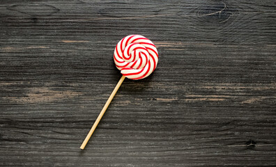 Red and white round candy on a stick on a wooden background