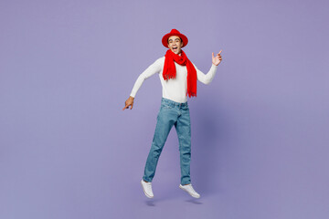 Poster - Full body side view happy smiling young middle eastern man he wear white turtleneck red hat scarf point index finger aside on workspace area jump high isolated on plain pastel light purple background.