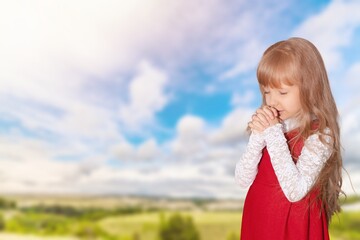 Wall Mural - Happy young child praying on big field background.