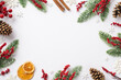 Leinwandbild Motiv Christmas Eve concept. Top view photo of fir branches in frost mistletoe berries pine cones cinnamon sticks dried orange slices snowflakes on isolated white background with blank space in the middle