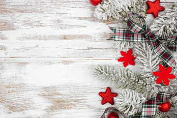 Wall Mural - Christmas side border of red ornaments, snowy branches and  plaid ribbon. Above view on a white wood background. Copy space.