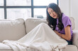 Unhappy asian woman worry have problem or menstrual pain sitting on sofa at home. Unwell young girl sick stomach ache menstrual pain tummy unhealthy disease menses sitting on couch. Health insurance.