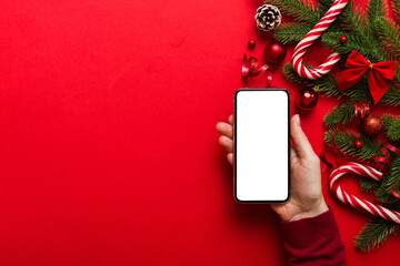 Wall Mural - christmas mockup with space for text. christmas advertising, app template. hand holding phone with empty screen on table background. Happy New Year and Xmas Flat lay