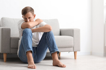 Canvas Print - Stressed young man sitting on floor at home