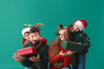 Little children surprising their parents with Christmas gifts on green background