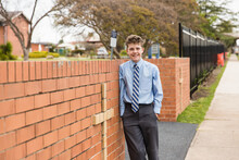 Boy in school uniform leaning on brick entrance with cross to private catholic school