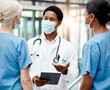 © Emily N/peopleimages.com - Face mask, covid and team of doctors with tablet doing research or checking test results in clinic. Medical, hospital and group of healthcare workers in collaboration on mobile device during pandemic
