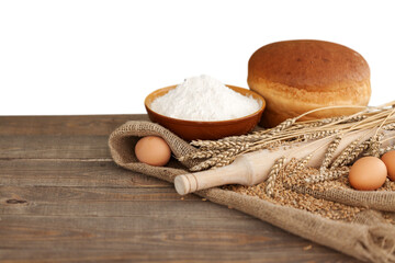 Wall Mural - Wheat ears and flour on wooden table isolated on white background