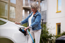 Senior Woman Charging Electric Car