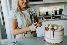 Woman In Kitchen Decorating Cake