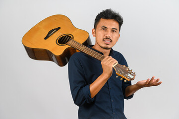 Wall Mural - Portrait of Young Asian man carrying an acoustic guitar isolated on white background