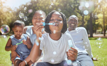 Happy, Nature And Black Family Blowing Bubbles While Playing, Bonding And Enjoying Summer In The Park. Happiness, Father And Mother With Children Having Fun Together In A Green Garden In South Africa