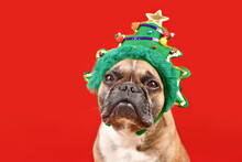 French Bulldog Dog Wearing Funny Christmas Tree Headband On Red Background With Copy Space