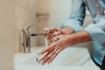  Man using soap and washing hands under the water tap. Hygiene concept hand closeup detail. 