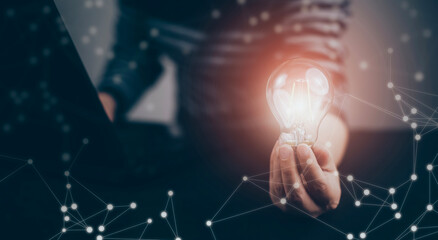 Poster - Businessman hand holding light bulb with icons and working on the desk, Creativity and innovation are keys to success.Concept of new idea and innovation with energy and power , working at home,