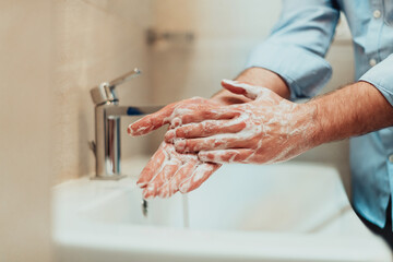 Man using soap and washing hands under the water tap. Hygiene concept hand closeup detail. 