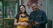 © Marco - An African American manager of small business holding tablet speaking with female employee at coffee shop entrance. Portrait of two diverse happy staff of restaurant cafe place
