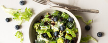 Bowl With Salad With Broccoli, Avocado And Blueberries On A Light Table