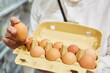 Kunde hält Pappkarton mit Eiern aus Freilandhaltung
