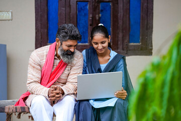Indian farmer daughter showing some detail in laptop to his father
