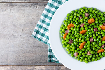 Wall Mural - Green peas with serrano ham and carrot on wooden table. Copy space